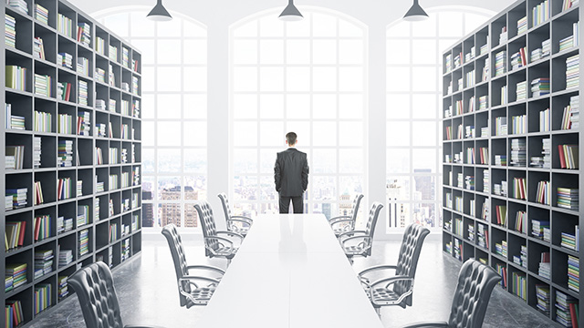 Business person looks out window of board room library